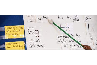 A teacher using a pointer across a white board giving phonemic instruction