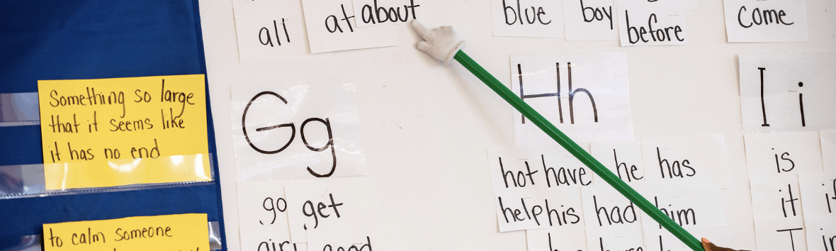 A teacher using a pointer across a white board giving phonemic instruction